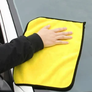 Eine Person wischt mit einem Mikrofaser-Reinigungshandtuch die Windschutzscheibe eines Autos ab.