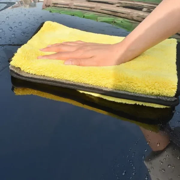 Eine Person reinigt ein Auto mit einem Mikrofaser-Reinigungshandtuch.