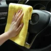 Eine Person, die ein Mikrofaser-Reinigungshandtuch verwendet, um das Lenkrad eines Autos zu reinigen.